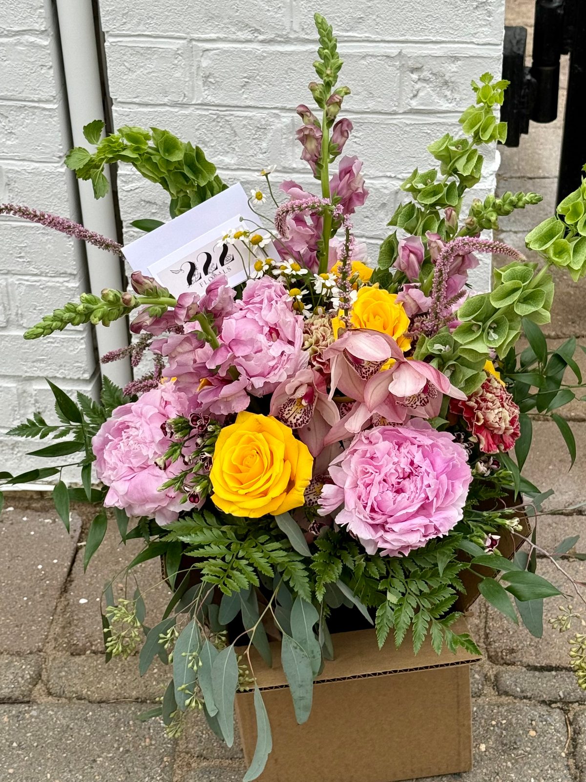 Pink peonies and yellow roses in delivery box